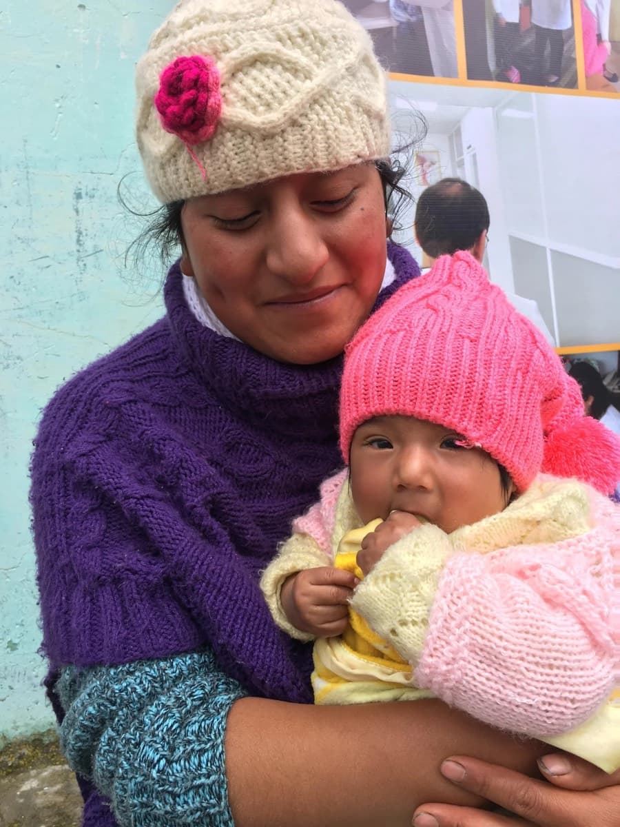 A woman holds a baby wrapped against the highland cold