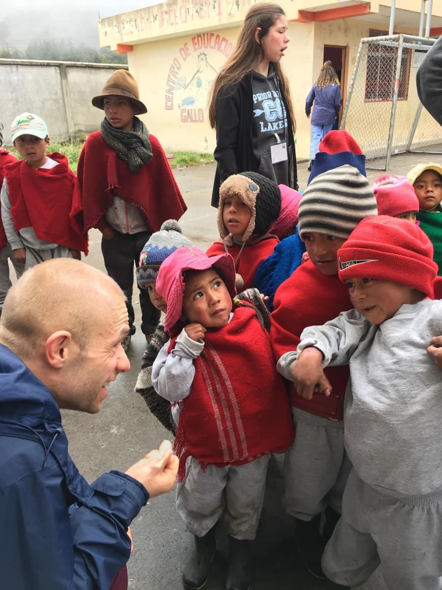 A volunteer surrounded by children in traditional highland dress