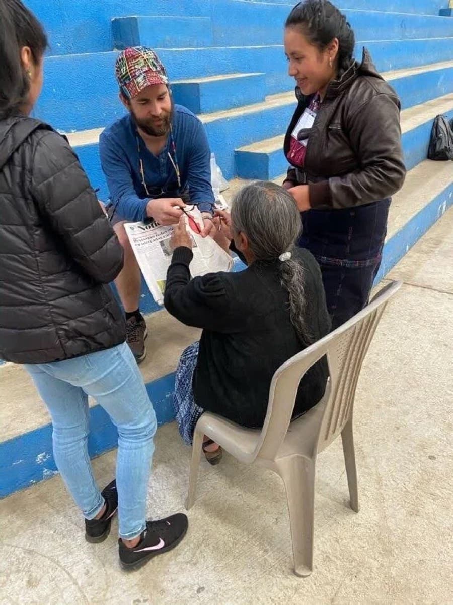 Clinicians examining an older patient seated outside the clinic