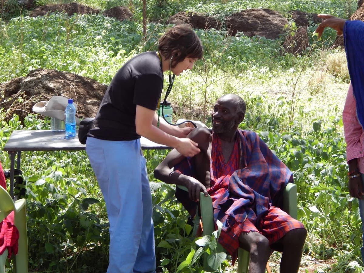 A clinician examines a Maasai patient in the shade of a tree
