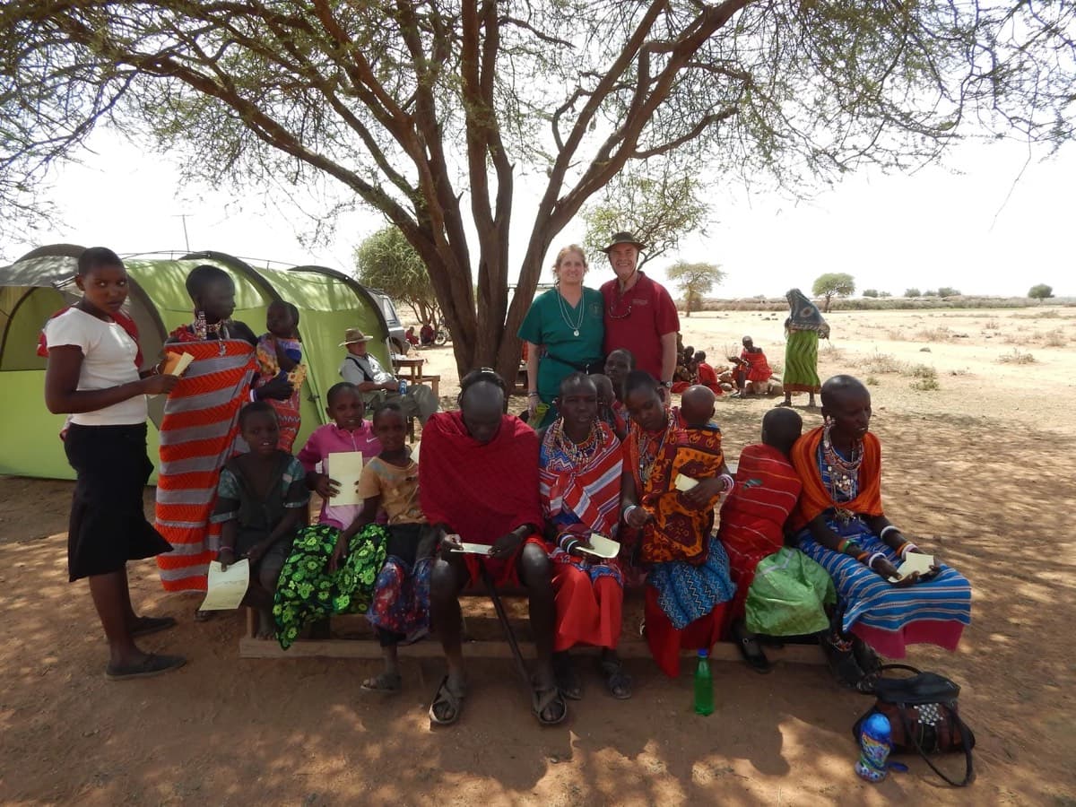 Community members gathered under a tree waiting to be seen
